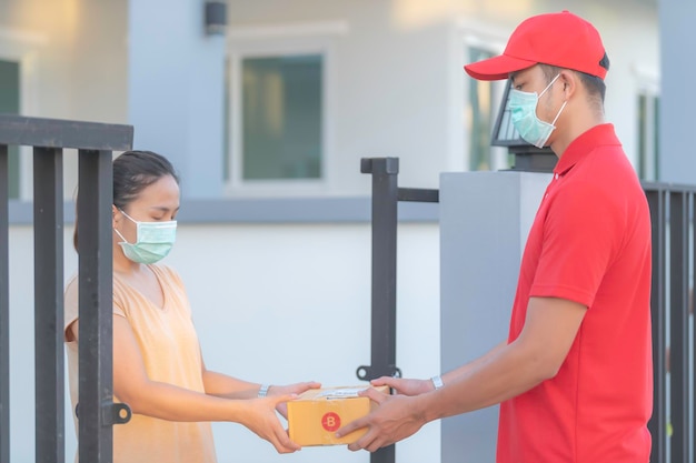 Азиатский доставщик носит защитную маску в красной формеКонцепция онлайн-доставки еды и продуктовНовая норма в covid19