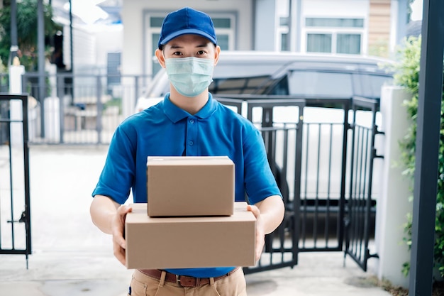 Asian Delivery man wearing mask send a package carton on front receiver shipping deliver social distancing while the virus is spreading and prevention crisis coronavirus covid19 front home customer