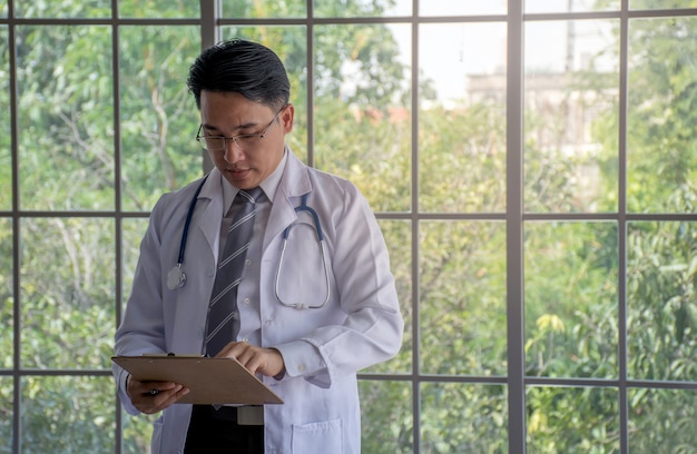 Asian doctor discuss documentation at a hospital with blurred window background