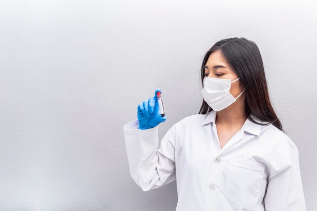 Photo asian doctor holding a test tube blood sample of coronavirus wearing lab coat