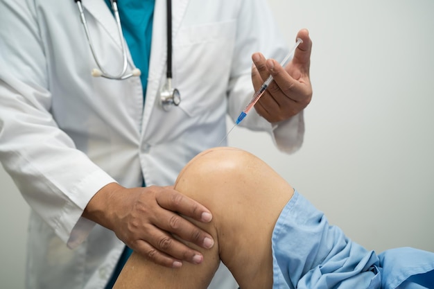 아시아 의사는 히알루론산 혈소판이 풍부한 혈장을 노인 여성의 무릎에 주사하여 통증 없이 걸을 수 있습니다