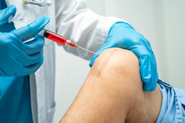 Asian doctor inject Hyaluronic acid platelet rich plasma into the knee of senior woman