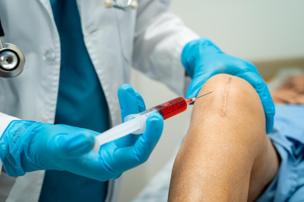 Asian doctor inject Hyaluronic acid platelet rich plasma into the knee of senior woman