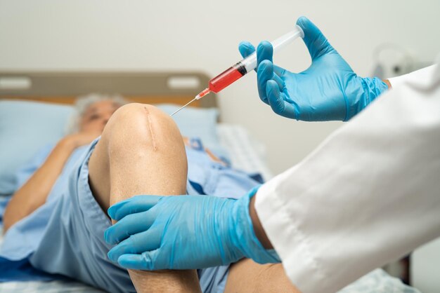 Foto un medico asiatico inietta plasma ricco di piastrine di acido ialuronico nel ginocchio.