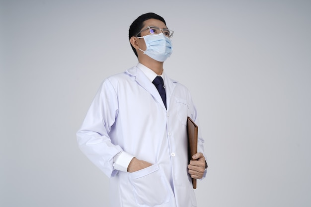 Asian doctor man wearing white coat, medical mask looking up with positive view