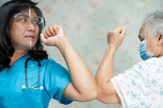 Asian doctor and old patient bump elbows for social distancing covid-19 coronavirus