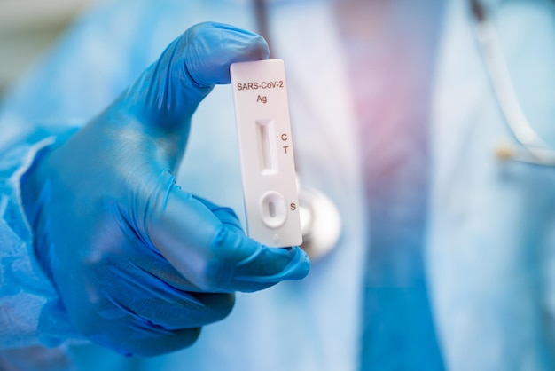 Asian doctor in ppe suit holding saliva antigen test kit for\
check covid19 coronavirus in hospital