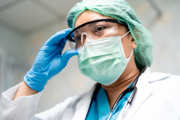 Asian doctor wearing eyeglass PPE suit to check patient