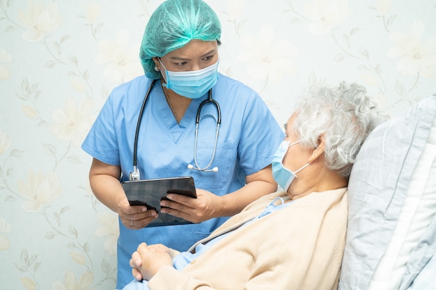 Asian doctor wearing face shield and PPE suit new to check patient