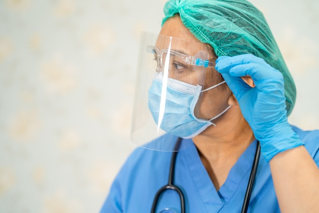 Medico asiatico che indossa una protezione per il viso e una tuta ppe nuova normalità per controllare la sicurezza del paziente infezione da covid-19 coronavirus scoppiata nel reparto infermieristico di quarantena.