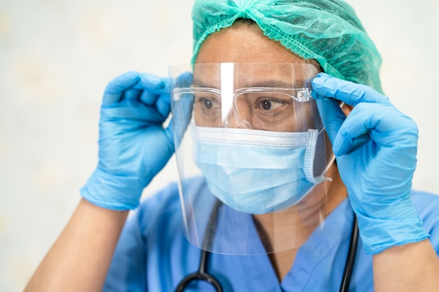 Asian doctor wearing face shield and PPE suit new normal to check patient protectCoronavirus