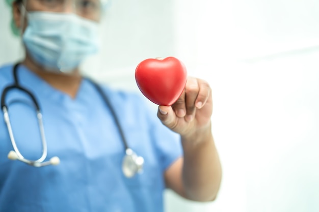 asian doctor wearing ppe suit to protect covid19 coronavirus holding red heart