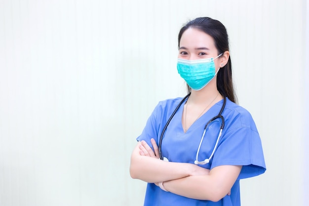아시아 의사는 호흡기를 보호하기 위해 청진기와 의료용 안면 마스크가 있는 의료 코트를 입는다