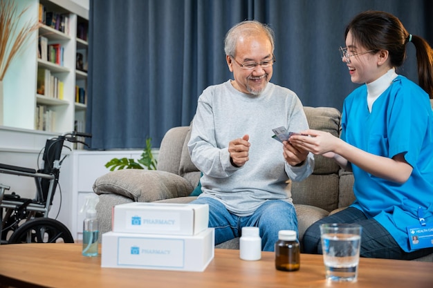 Asian doctor with physician visit senior male patient consult medicine dosage at house in living room, Woman nurse caregiver showing prescription drug to senior man at nursing home, healthcare support