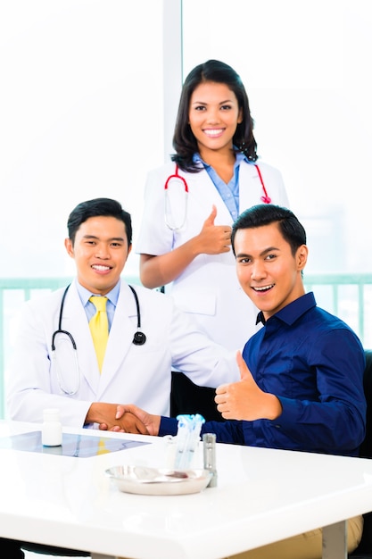 Asian Doctors with Patient in medical office or clinic