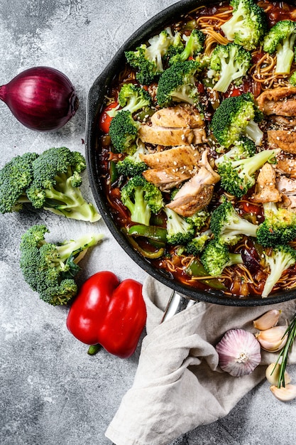 Asian egg noodles with vegetables and meat on cooking pan. Top view