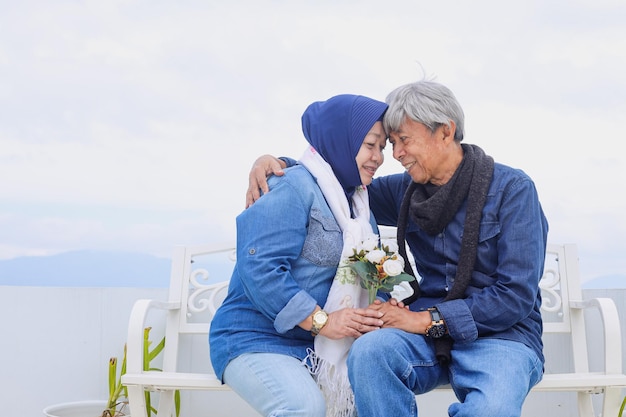 Coppie anziane asiatiche una coppia romantica senior sana è seduta e tiene insieme il fiore bianco