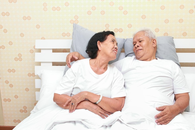 Asian elderly couple lying in bed in the bedroom happy smile\
family concept health care health insurance for seniors