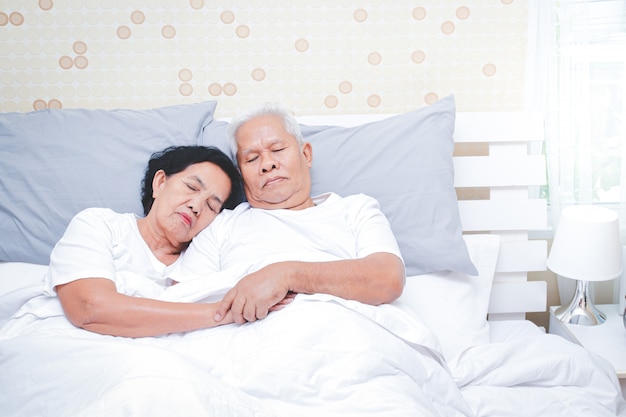 Asian elderly couple Sleep in bed in the bedroom.