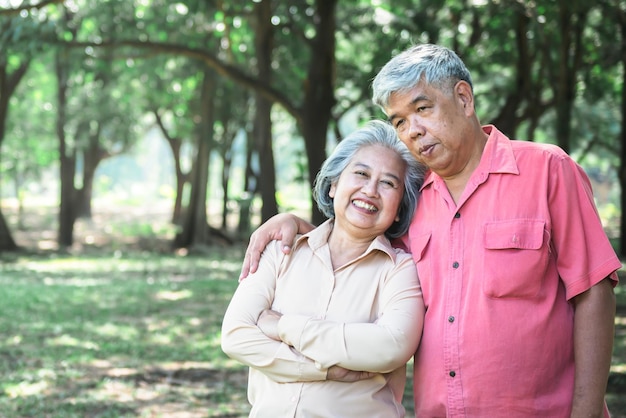 Asian elderly couple Standing under a big tree they are happy to elderly relaxation in the park