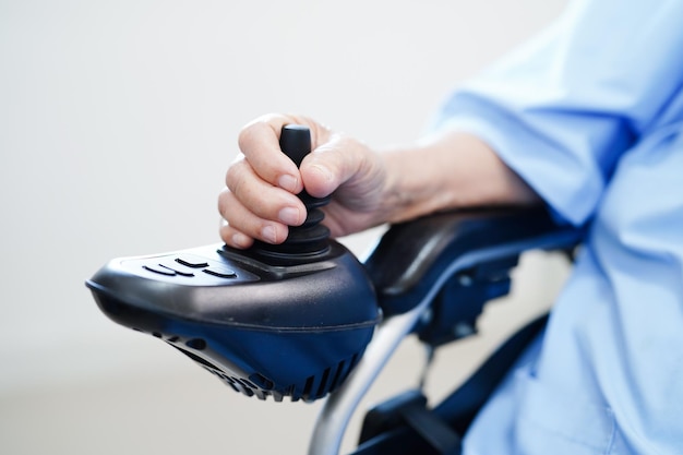 아시아 노인 장애 여성 환자가 병원에서 조이스틱 전기 체어를 사용합니다.