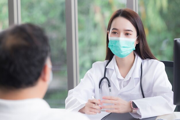 Asian elderly man patient consults with professional woman doctor about his symptom while doctor