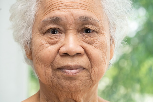 Asian elderly old woman face and eye with wrinkles portrait closeup view