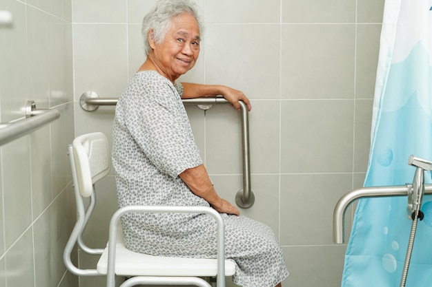 Asian elderly old woman patient use toilet support rail in bathroom handrail safety grab bar security in nursing hospital