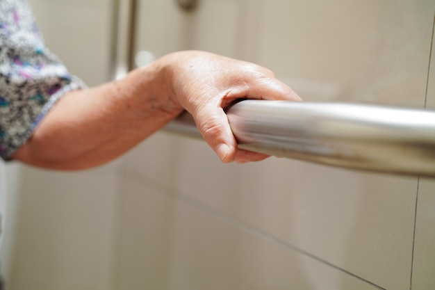 Asian elderly old woman patient use toilet support rail in bathroom handrail safety grab bar security in nursing hospital