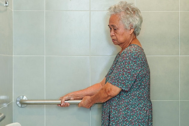 Asian elderly old woman patient use toilet support rail in bathroom handrail safety grab bar security in nursing hospital