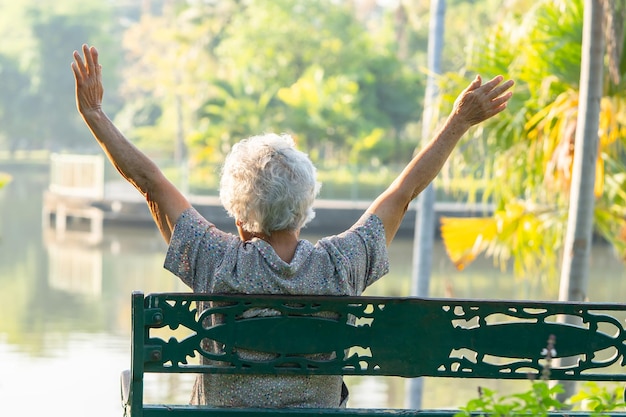 Asian elderly woman depressed and sad sitting back on bench in autumn park