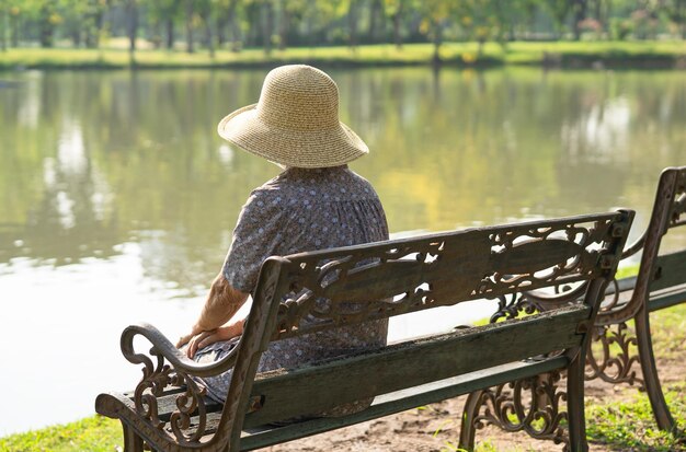 Asian elderly woman depressed and sad sitting back on bench in autumn park