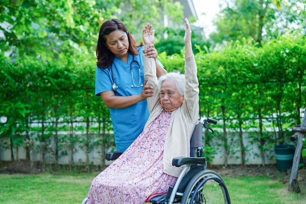 Asian elderly woman disability patient exercise on wheelchair with doctor in park medical concept