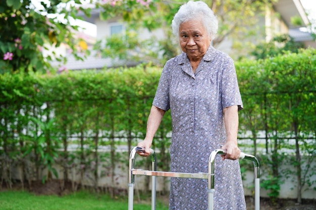 Asian elderly woman disability patient walk with walker in nursing hospital medical concept