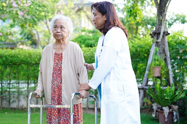 아시아 노인 여성 장애 환자가 공원 의료 개념에서 워커와 함께 걷습니다.