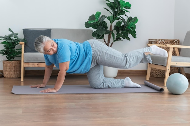 Asian elderly woman doing exercise at home by stretching the leg muscles