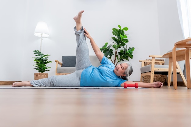 Asian elderly woman doing exercise at home by stretching the\
leg muscles