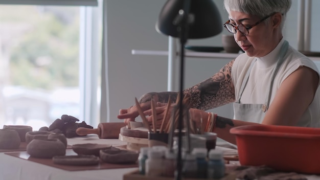 Foto donna anziana asiatica che si gode il lavoro di ceramica a casa una ceramista femminile sta realizzando nuove ceramiche in uno studio