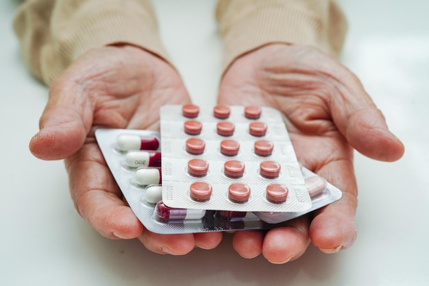 Asian elderly woman holding pill drug in hand strong healthy medical concept