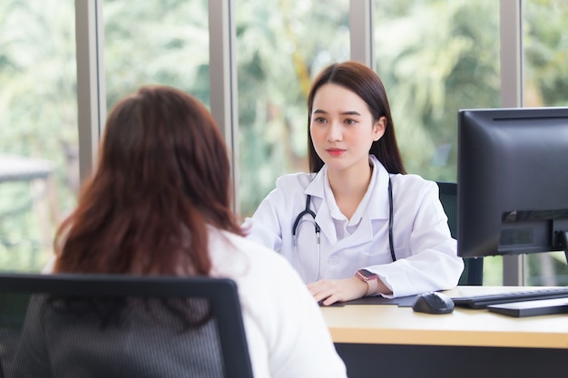 Asian elderly woman patient is checked health by doctor explaining while both wear medical face mask