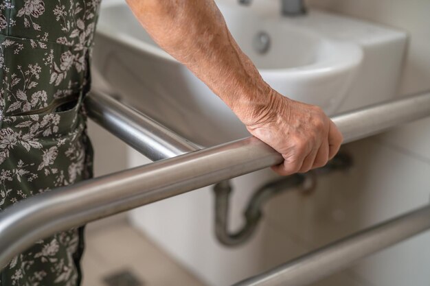 Asian elderly woman patient use toilet bathroom handle security in nursing hospital healthy