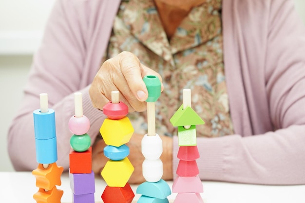 Фото Азиатская пожилая женщина играет в головоломку для лечения, профилактики деменции и болезни альцгеймера