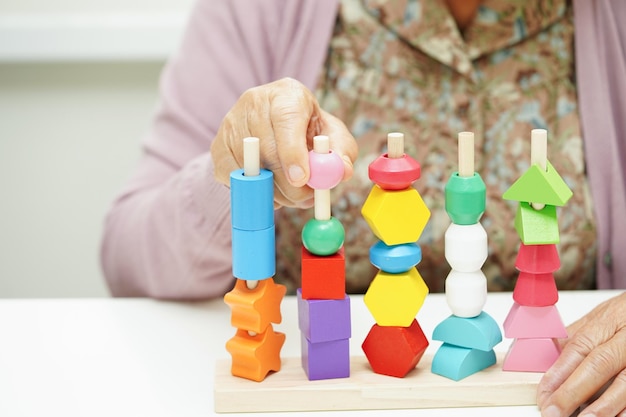 Asian elderly woman playing puzzles game for treatment dementia prevention and Alzheimer disease