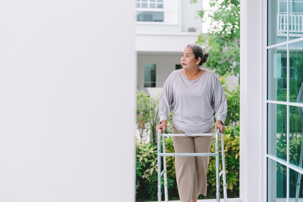 Asian elderly woman using walking frame at homewhite hair woman\
walking to exercise at home