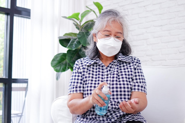 Asian elderly women wearing white masks Spray alcohol on your hands to clean and prevent the coronavirus The concept of patients staying at home