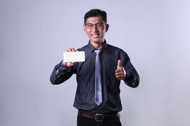 An Asian employee holding smartphone and giving thumbs up with an excited expression