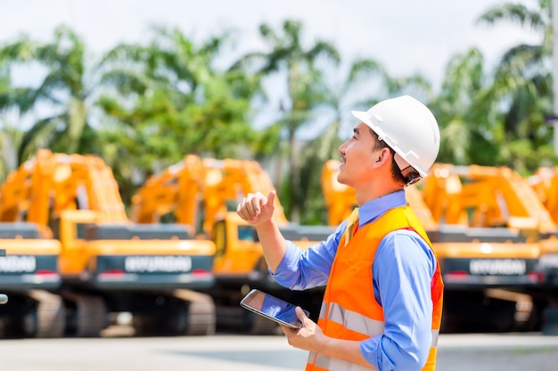 Asian engineer checking plans on construction site