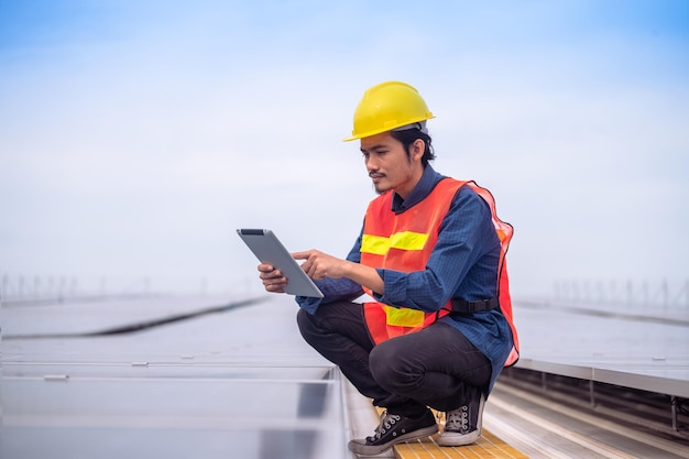 Asian Engineer checking solar power cell energy on rooftop of factory