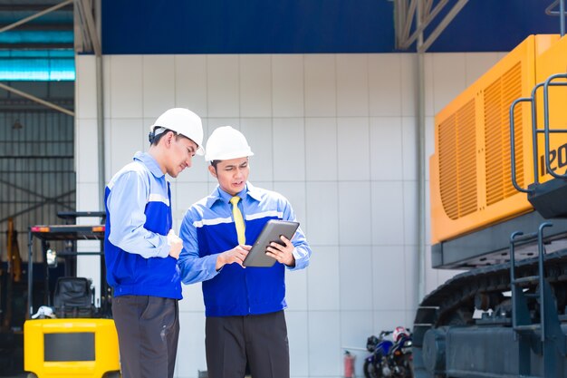 Asian engineer controlling construction machinery of construction site