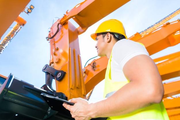 Asian engineer controlling shovel excavator 